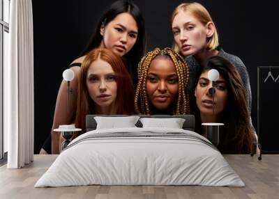 mixed race group of ladies isolated on black background, young women of different ethnicity seriously looking at camera Wall mural