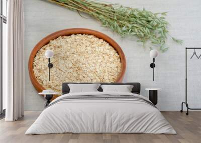 Oatmeal in a brown ceramic bowl with on a background of green ripe ears of oats on a linen tablecloth. Wall mural