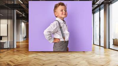 portrait of beautiful caucasian little child boy posing at camera isolated over purple background, kid looks at camera and smile Wall mural