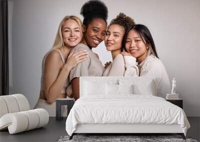 Portrait of four happy beautiful diverse young women with perfect skin posing for camera while standing isolated over white studio background. Attractive ladies in casual clothes are friends Wall mural