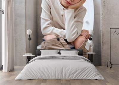 School boy is sitting on toilet with suffering from constipation or hemorrhoid. caucasian kid is on wc seat, bored and tired, have rest relaxed. hygiene, health care concept Wall mural