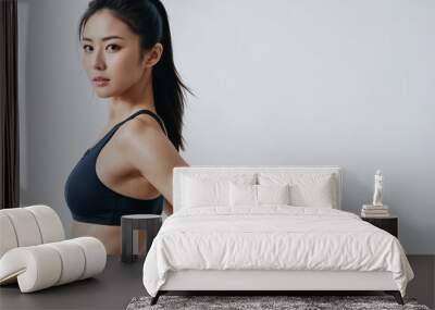 Young Asian fit sexy woman standing isolated on a gray background. Studio portrait of a healthy muscular female. Wall mural