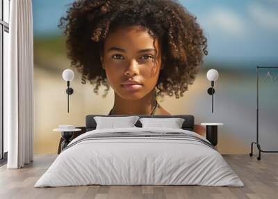 a beautiful young african dark-skinned woman posing for a photo at the beach on a vacation in summer, the sea or ocean water behind her Wall mural