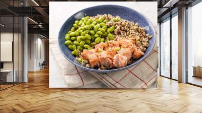 A green bowl with quinoa tricolore, roughly chopped and pulled salmon and teamed green soy beans edamame on light background Wall mural