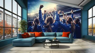 A group of girls - a female football sports team in red uniform cheering because of victory in a game after making a goal at the stadium or a soccer field Wall mural