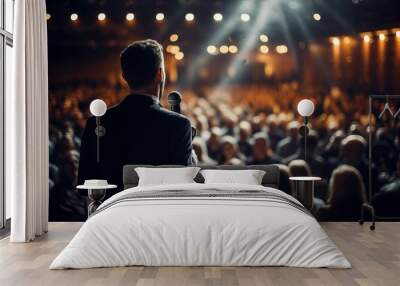 a male motivational speaker or a stand-up comedian presenting his speech in front of an audience in a microphone in a dark club or concert hall venue with selective lighting Wall mural