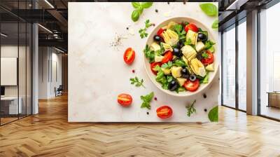 a top view on a bowl with colorful healthy salad with artichokes, tomatoes, lettuce, broccoli, olives and herbs on a beige colored concrete background, copy space for text Wall mural