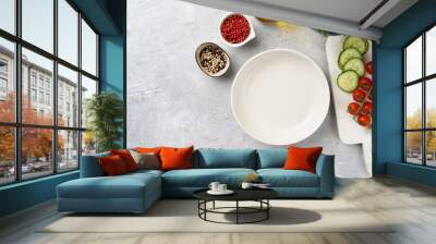 Empty white bowl, small dip plates with chilli pepper and black pepper, fresh thyme, cucumber slices on grey concrete surface. Copy space, top view Wall mural