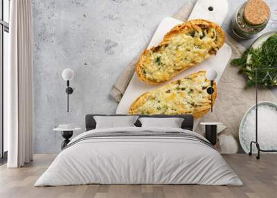 Two halves of garlic and butter bread - baguette on a marble board, sea salt, pepper, dill and garlic cloves on a grey concrete background, top view Wall mural