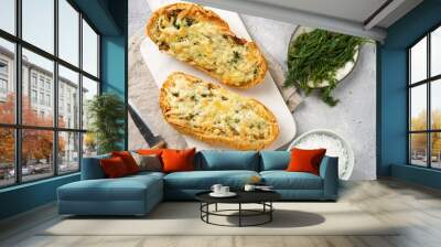 Two halves of garlic and butter bread - baguette on a marble board, sea salt, pepper, dill and garlic cloves on a grey concrete background, top view Wall mural