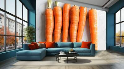 A bundle of freshly harvested organic carrots with vibrant green tops displayed on a marble surface for natural food presentation. Wall mural