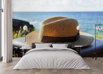 Straw hat on suitcase by ocean: relaxation and travel concept with summer beach vibes Wall mural