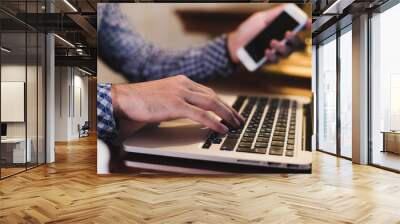 Close up male hands holding big smart phone while connecting to wireless, businessman using technology sitting at wooden desk Wall mural