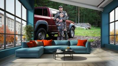 Happy hunter with his son near their pickup truck before hunting in a forest Wall mural