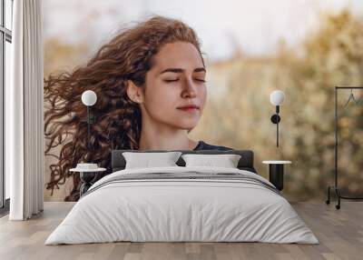 Face of a woman dreaming with closed eyes outdoors. Curly hair. Autumn. Wall mural