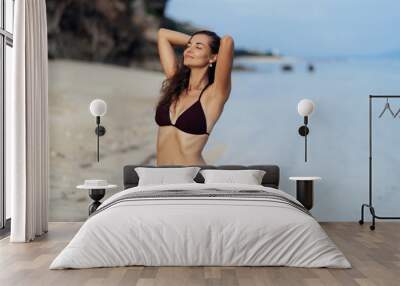 Beautiful happy girl in black swimwear relaxing on beach with white sand Wall mural