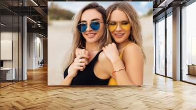 Close-up portrait of two beautiful girls in swimsuits hugging on the beach. Wall mural