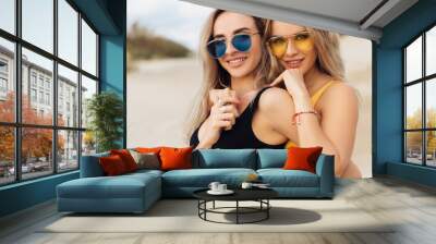 Close-up portrait of two beautiful girls in swimsuits hugging on the beach. Wall mural