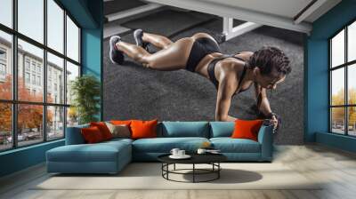 attractive young woman is doing plank exercise while working out in gym Wall mural