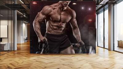 Male athlete bodybuilder posing on a black background Wall mural