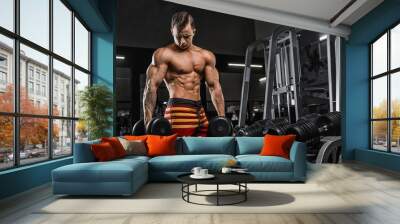 Muscular athletic bodybuilder man hard workout in gym over dark background with dramatic light with barbell Wall mural