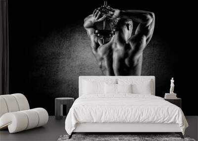 Muscular man raising behind his head dumbbells Wall mural