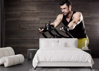 muscular mature man doing aerobics elliptical walker in modern f Wall mural