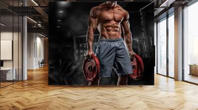 Young male athlete bodybuilder posing and doing sports exercises in the gym Wall mural