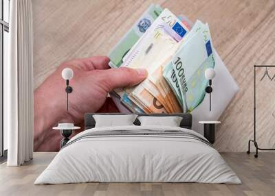 mens hand holding white envelope full of euro bills Wall mural