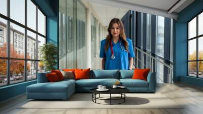 Smiling female medical worker in blue uniform with stethoscope at clinic Wall mural