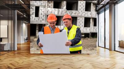 two workers in overalls and helmets developed a construction plan for the construction site Wall mural