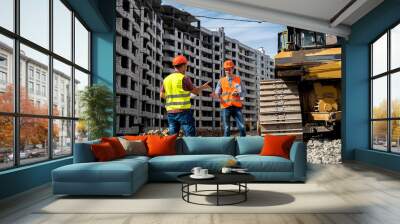 two young workers in overalls stand with their backs looking at the new building Wall mural