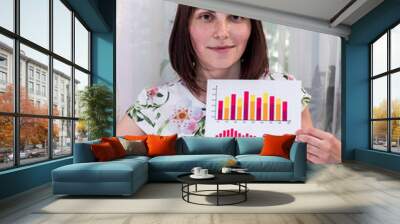 Woman analyst showing business graph and pointing on it Wall mural