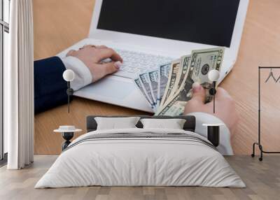 woman holding dollar currency on white laptop Wall mural