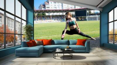 Young sportive woman making morning exercises outdoors on the stadium Wall mural