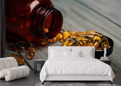 Fish oil capsules with omega 3 and vitamin D in a glass bottle on wooden texture, healthy diet pills Wall mural