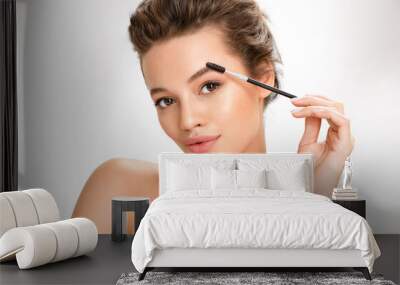 Young girl using brush for eyebrows. Photo of  girl with perfect makeup on white background. Beauty and skin care concept Wall mural