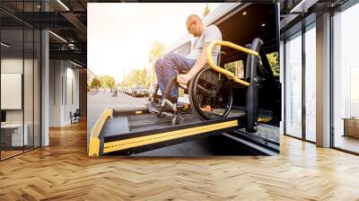 A man in a wheelchair on a lift of a vehicle for people with disabilities Wall mural