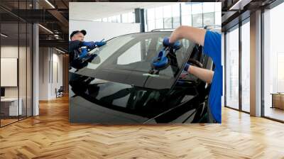 Automobile special workers replacing windscreen or windshield of a car in auto service station garage. Wall mural