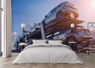 Car carrier trailer transports cars on highway at blue sky background. Wall mural