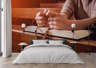 Christian woman praying in church. Hands crossed and Holy Bible on wooden desk. Wall mural