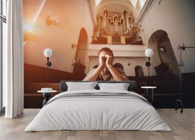 Christian woman praying in church. Hands crossed and Holy Bible on wooden desk. Wall mural