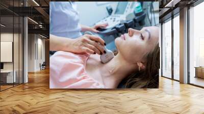 Doctor using ultrasound scanning machine for examining a thyroid of woman Wall mural