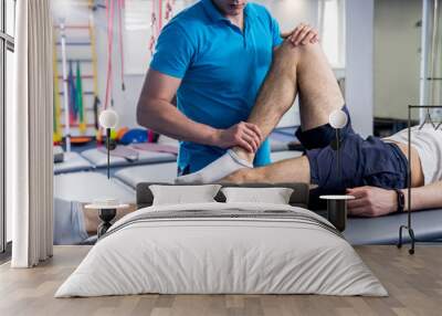 Rehabilitation therapy. Physiotherapist working with young male patient in the rehabilitation center Wall mural