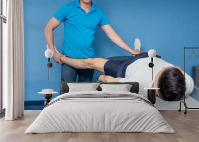 Rehabilitation therapy. Physiotherapist working with young male patient in the rehabilitation center Wall mural