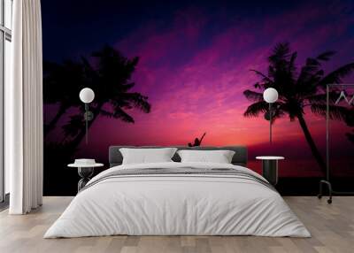 Silhouette of couple on tropical beach during sunset on background of palms and sea Wall mural