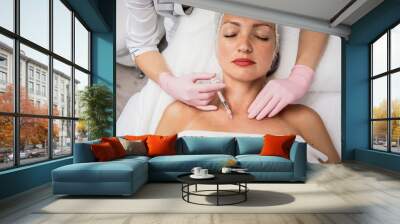 The doctor cosmetologist makes the neckline injections procedure. Young woman in a beauty salon. Wall mural