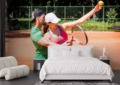 Young athletic woman playing tennis with her coach. Wall mural