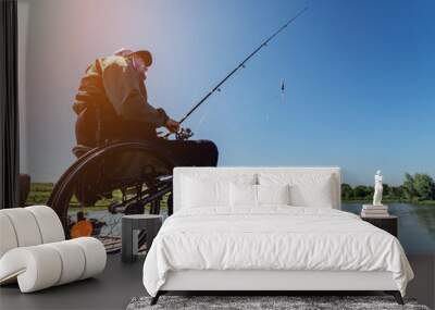 Young disabled man in a wheelchair fishing. Wall mural