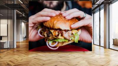 Young man eating a cheeseburger. Wall mural